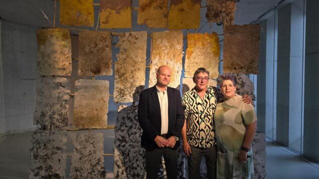 «Arrels Mediterrànies» abre Alere/Dolia 2026 con el arte de Ximo Canet como puente entre el mar y la tierra 12 Tres personas posan frente a la instalación artística de paneles texturizados de Ximo Canet durante su inauguración.