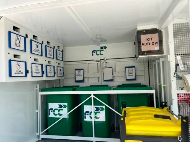 Imagen: Interior del ecoparque móvil con contenedores verdes de FCC y compartimentos etiquetados para distintos tipos de residuos reciclables.