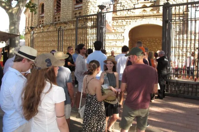 Grupo de personas haciendo cola frente a la entrada de piedra de la plaza de toros de Ondara.