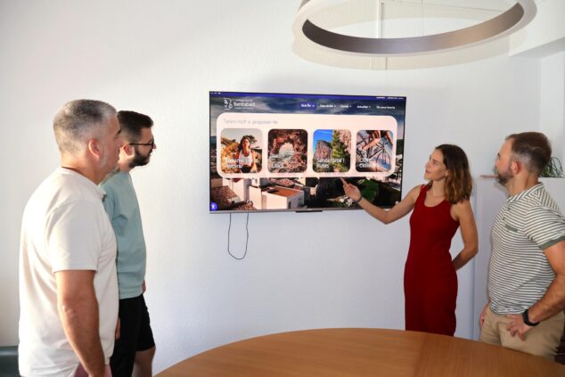 Cuatro personas observan una pantalla gigante donde se muestra la interfaz de la nueva página web turística de Benitatxell.