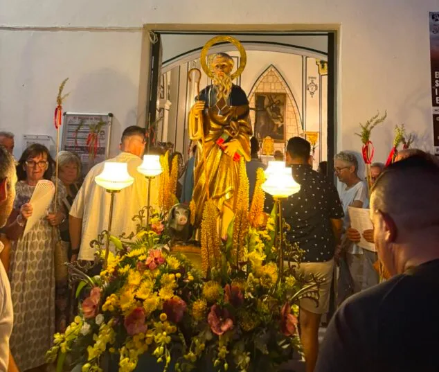 Imagen: Estatua de San Antonio Abad sobre un anda con flores y lámparas, saliendo de una iglesia durante una procesión nocturna en Pamis.