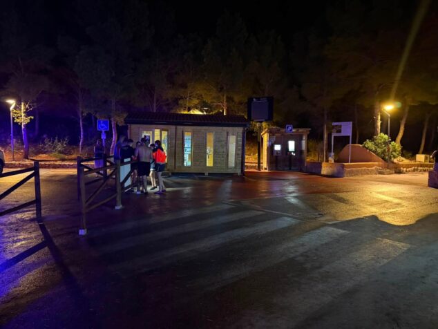 Grupo de personas y servicios de emergencia de noche tras el rescate en Cala Testos.