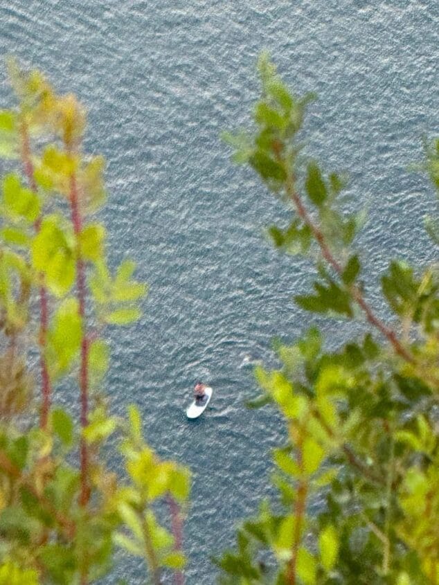 Imagen: Vista aérea de una persona sobre una tabla de paddle surf en el mar con oleaje.
