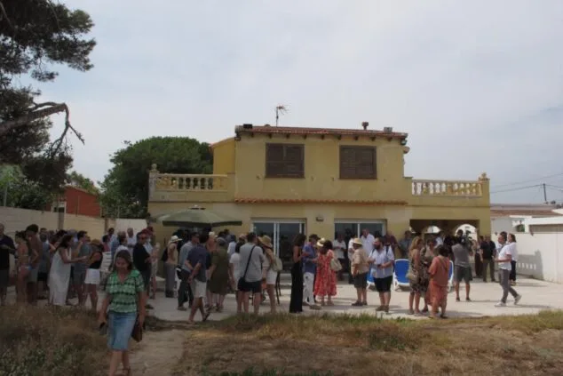 Numerosas personas reunidas en el patio de una casa durante un encuentro sobre la ley de costas en Dénia.