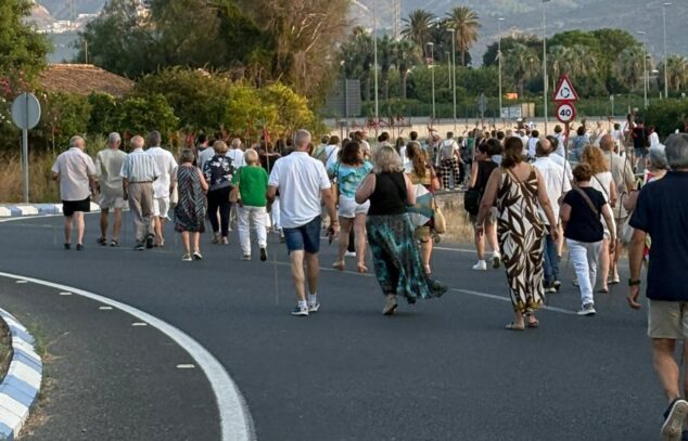Pamis despide sus fiestas patronales a Sants de la Pedra con gran participación y convivencia 6 Imagen: Un gran grupo de personas camina por una carretera rural durante la romería de las fiestas de Pamis al atardecer, con montañas al fondo.