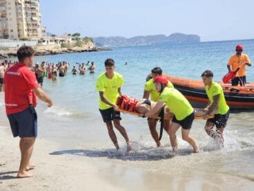 Varios socorristas sacan en camilla a una persona del agua hacia la playa durante un simulacro de rescate.