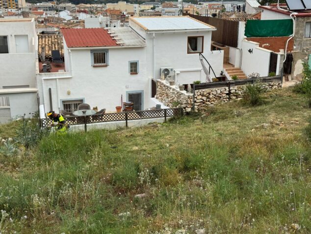 Pedreguer actúa contra incendios con un gran desbroce en dos zonas montañosas 8 Operario desbrozando una ladera con vegetación cerca de casas en Pedreguer.