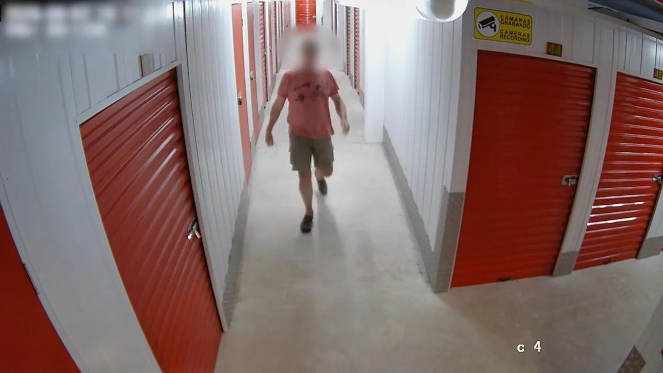 Pasillo de trasteros con puertas rojas captado por una cámara de seguridad.