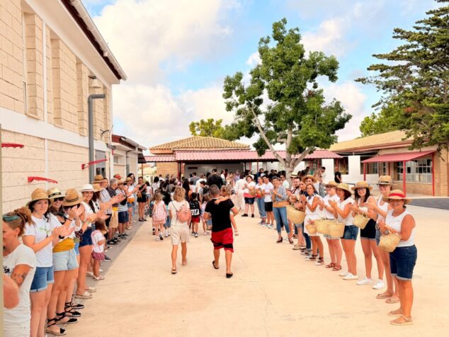 Profesores formando un pasillo y aplaudiendo mientras los alumnos y familias entran al patio del colegio.
