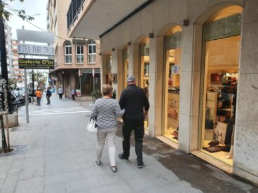 Vista de una calle céntrica en Calp con varios locales comerciales y personas paseando.