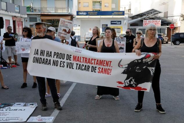 Un grupo de manifestantes sostiene una gran pancarta blanca con letras negras y rojas que dice 'JA HI HA PROU DE MALTRACTAMENT. ONDARA NO ES VOL TACAR DE SANG!' y un dibujo de un toro, durante una protesta en la calle.