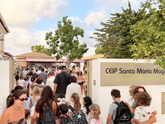 Multitud de familias y alumnos entrando por la puerta principal del colegio CEIP Santa María Magdalena, cuyo cartel es visible a la derecha.