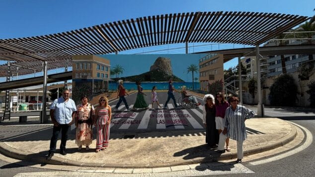 Imagen: Grupo de seis personas posando frente a un mural grande y colorido sobre los derechos de las mujeres en una estación de autobuses al aire libre en Calp, con el Peñón de Ifach al fondo.