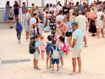 Alumnos con mochilas y sus familias en el patio del CEIP Santa María Magdalena.
