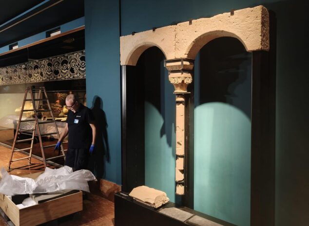 Imagen: Operario instalando el ventanal gótico de piedra en el interior del museo MARQ rodeado de material de embalaje.