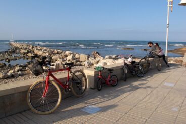 Diverses bicicletes aparcades en un passeig marítim de pedra al costat del mar a la Marina Alta.