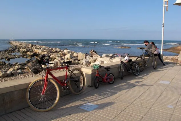 Imagen: Diverses bicicletes aparcades en un passeig marítim de pedra al costat del mar a la Marina Alta.