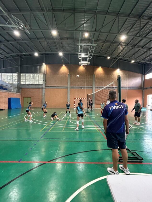 Imagen: Varias jugadoras disputan un punto durante un partido de voleibol en un gimnasio cubierto.