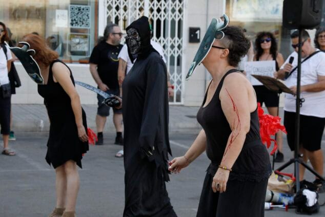 Activistas disfrazados con máscaras de toro y de la muerte durante una protesta antitaurina en una plaza pública.