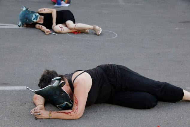 Imagen: Dos activistas con máscaras de toro y sangre simulada yacen en el suelo durante una protesta antitaurina.