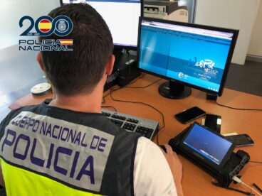 Alertan de un nuevo método de estafa donde los ciberdelincuentes suplantan cuentas de WhatsApp 2 Un agente de la Policía Nacional de espaldas frente a dos monitores de ordenador y varios teléfonos móviles en una mesa de oficina.