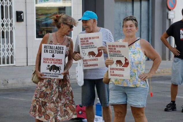 Tres personas mayores sosteniendo carteles de protesta contra las subvenciones a la tauromaquia y los tiempos de espera en sanidad.