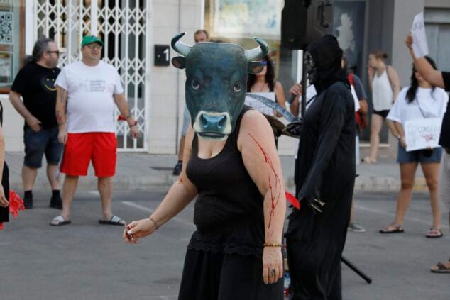 Imagen: Persona con máscara de toro realista y sangre falsa en el brazo durante una protesta antitaurina.