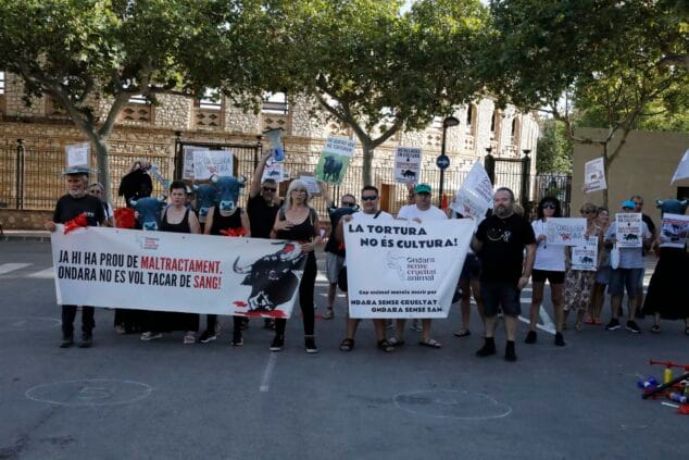 Grupo de manifestantes de 'Ondara sin crueldad animal' sosteniendo pancartas contra la tauromaquia frente a una plaza de toros.