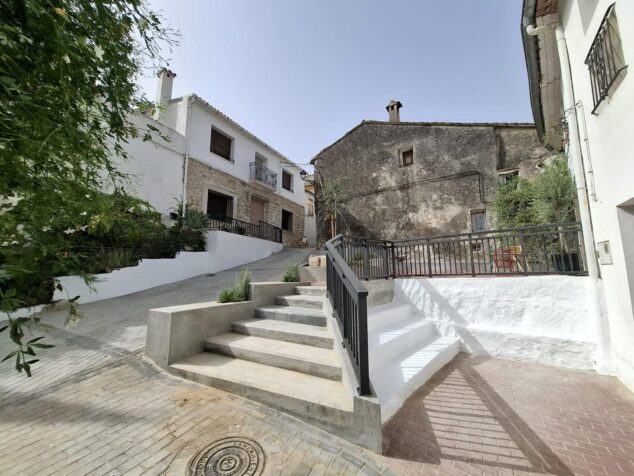 Benirrama estrena Plaça de Baix mejorada con la participación ciudadana y el Pla Conviure 3 Imagen: Nuevas escaleras de hormigón con barandillas metálicas negras y pavimento de adoquines en la renovada Plaça de Baix de Benirrama.