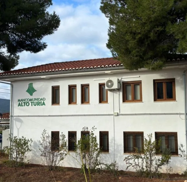 Imagen: Fachada blanca del edificio de la Mancomunidad Alto Turia con su logotipo y nombre en verde.