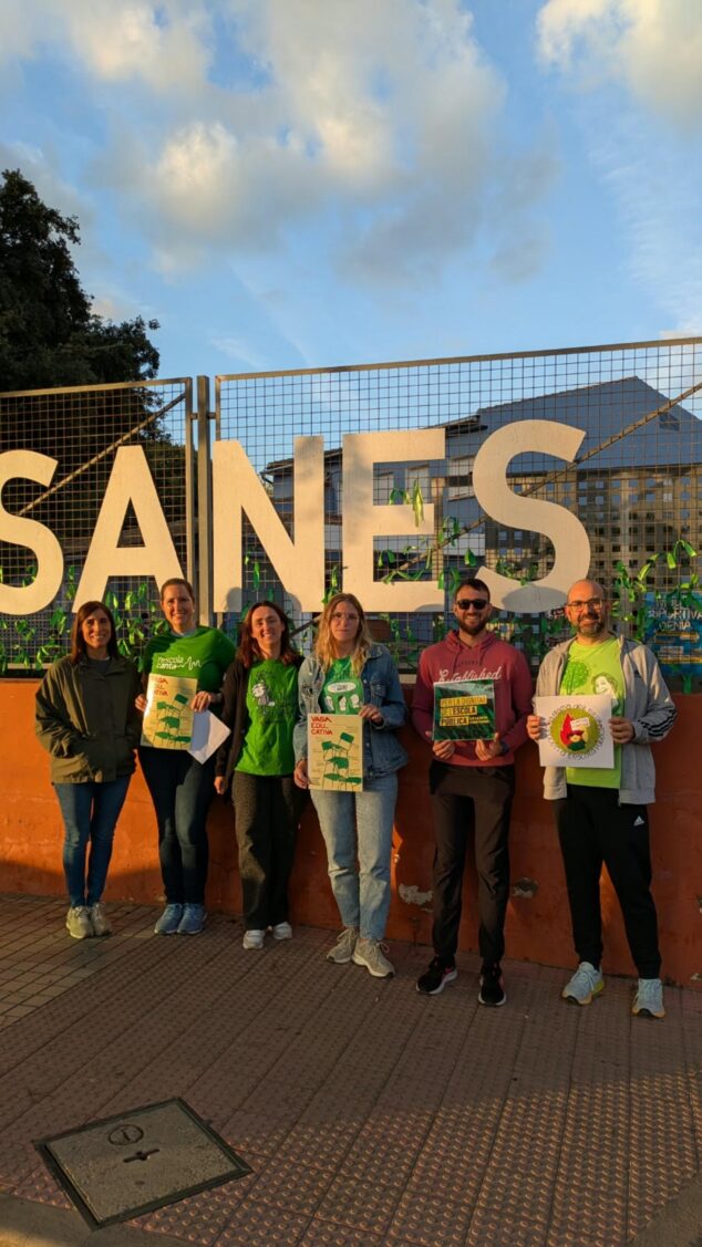 Imagen: Grupo de seis docentes con camisetas verdes y carteles reivindicativos frente a las letras gigantes del CEIP Les Vessanes en Dénia.