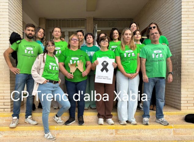 Docentes del CP Trenc d'Alba de Xàbia concentrados con camisetas verdes y un cartel solidario.
