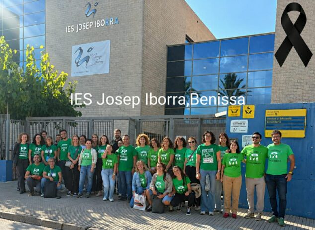 Imagen: Grupo de profesores y personal con camisetas verdes concentrados frente a la fachada del IES Josep Iborra de Benissa, con un lazo negro en la esquina superior.