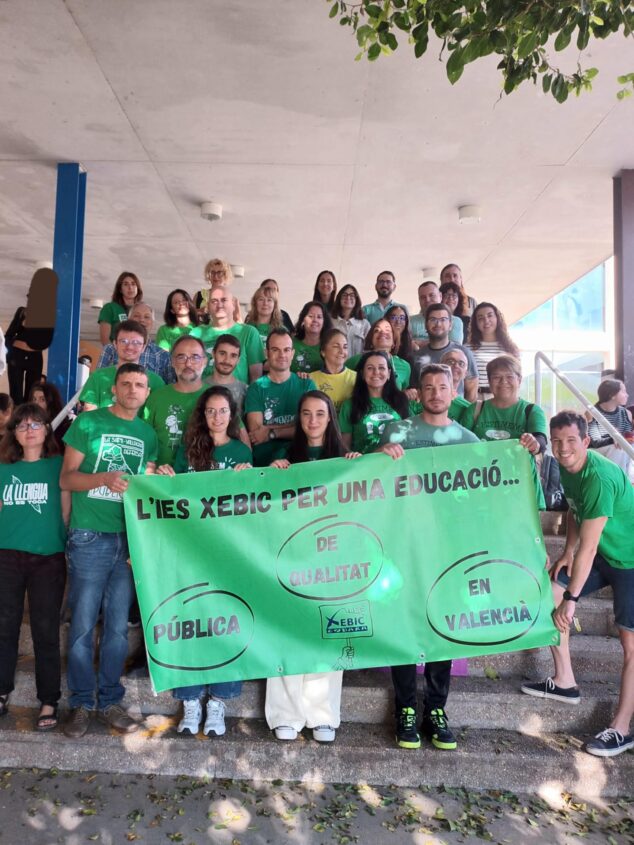 Imagen: Grupo de profesores con camisetas verdes y una pancarta verde frente al IES Xebic de Ondara durante una protesta.