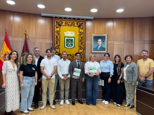 Calp explora un hermanamiento con la ciudad francesa de Neuilly-sur-Marne 3 Imagen: Grupo de doce personas, delegaciones de Calp y Neuilly-sur-Marne, posando en una sala oficial con banderas y un escudo.
