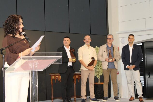 Cultura, historia y danza protagonistas en la celebración del 9 d’Octubre en Ondara 3 Imagen: Una mujer habla en un atril en un escenario mientras tres hombres sostienen premios y otro hombre observa a su lado.