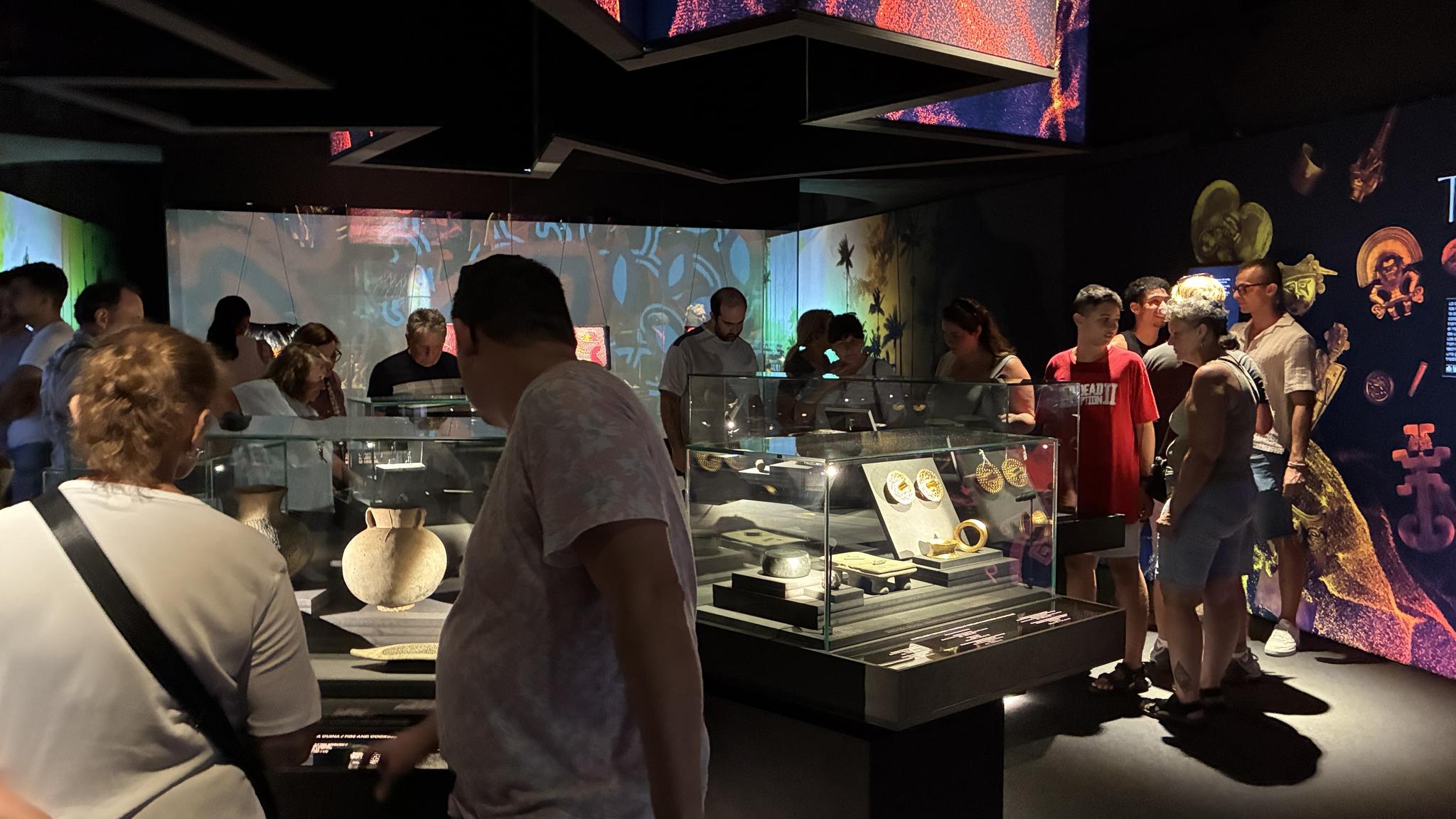 Visitantes observando vitrinas con objetos de oro en la exposición "El oro y el universo" del museo MARQ.