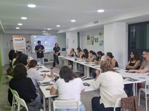 Imagen: Fotografía de una sesión de formación con ponentes y un grupo de profesionales sentados en mesas.