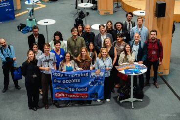 Foto de familia de los participantes en la jornada con la pancarta contra las %22fábricas de peces%22