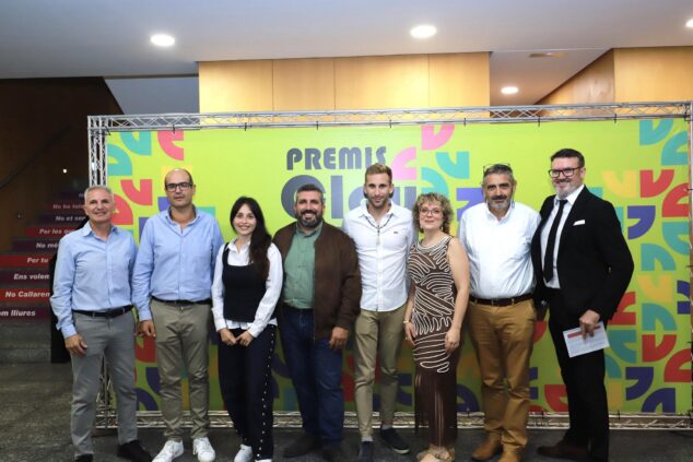 El Verger entrega sus II Premis Clau y homenajea a Elvira Salort por toda una vida dedicada al comercio 3 Imagen: Siete personas posan de pie frente a un fondo verde con el logotipo de "Premis Clau El Verger".