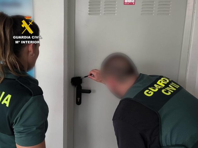 Detenidos tres ladrones que robaron en lavanderías de la Marina Alta 1 Imagen: Agentes de la Guardia Civil examinando la cerradura de una puerta con herramientas.