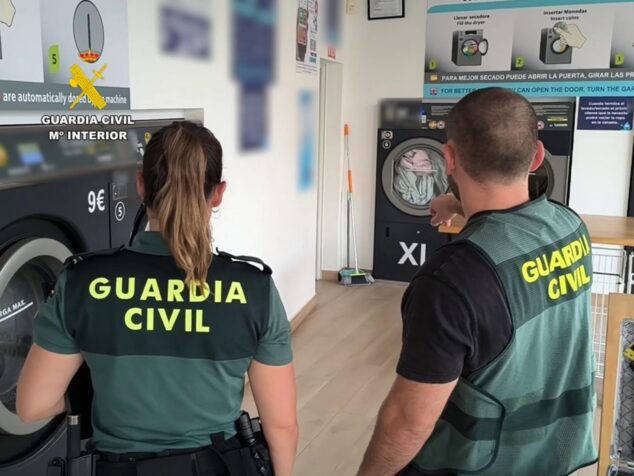 Detenidos tres ladrones que robaron en lavanderías de la Marina Alta 2 Imagen: Dos agentes de la Guardia Civil de espaldas dentro de una lavandería de autoservicio.