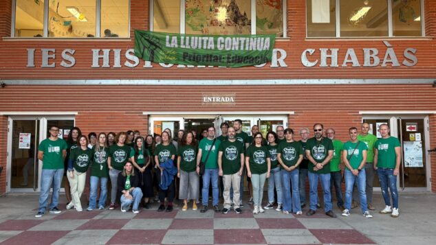Imagen: Grupo de profesores del IES Historiador Chabàs de Dénia concentrados con camisetas verdes y una pancarta en la entrada del instituto.