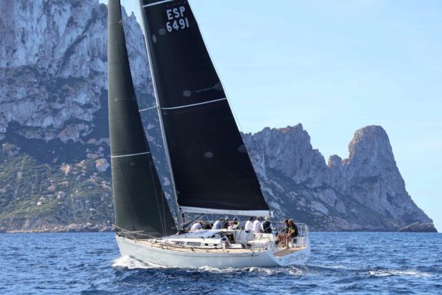 Imagen: El velero Jeffertje 3 navegando en el mar con la costa rocosa de fondo durante la regata.