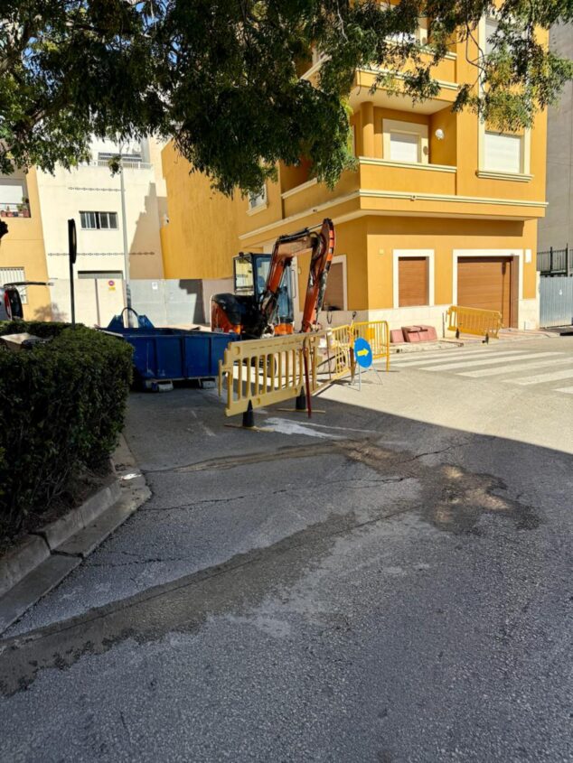 Imagen: Excavadora naranja y zona de obras delimitada con vallas amarillas en una calle de Teulada.
