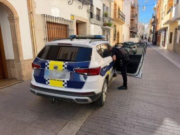 Coche patrulla de la Policía Local de Calp con un agente en una calle estrecha.