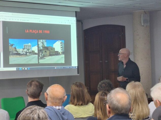 Imagen: Robert Miralles hablando frente a una pantalla con fotos antiguas durante la presentación de su libro en Ondara.