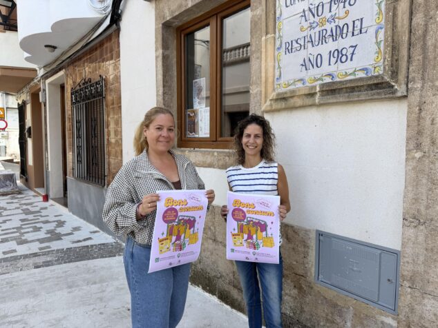 Impulso al comercio local: Benitatxell lanza su Bono Consumo con cheques de hasta 110 euros 1 Imagen: Dos mujeres sosteniendo carteles promocionales de la campaña 'Bons Consum' en una calle.
