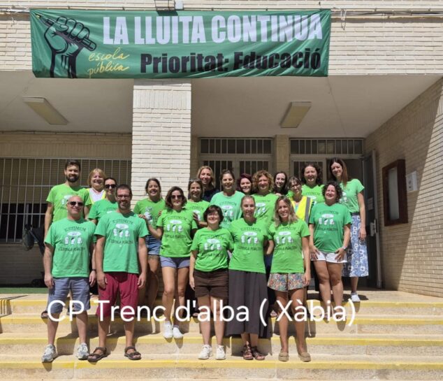 Imagen: Profesorado del CP Trenc d'Alba de Xàbia concentrado con camisetas verdes y una pancarta que dice "LA LLUITA CONTINUA escola pública Prioritat: Educació".