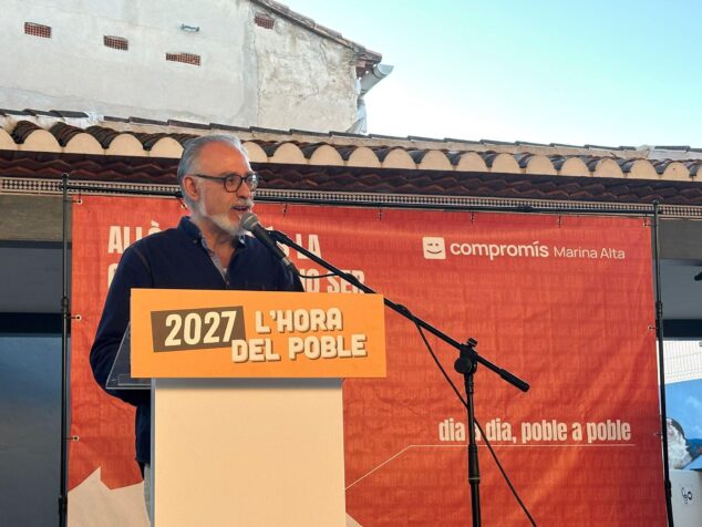 Sergi Ferrús Peris anuncia su candidatura a las primarias de Compromís por Alacant 1 Imagen: Sergi Ferrús Peris hablando en un atril durante un acto de Compromís, con una pancarta detrás que dice '2027 L'HORA DEL POBLE'.